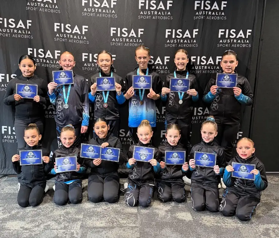Group of young sport aerobics athletes posing with participation certificates and medals at a FISAF Australia Sport Aerobics event.